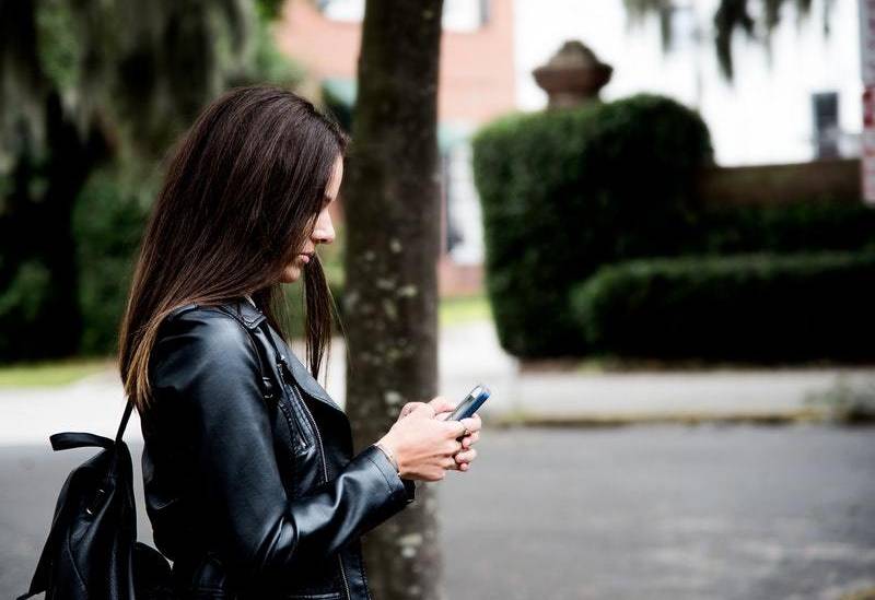 side view of woman typing on her phone outside