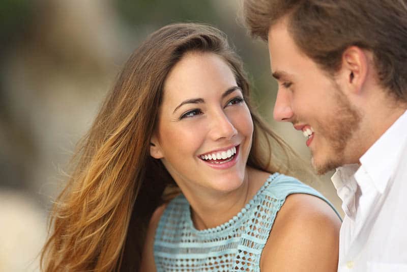 pareja sonriente mirándose al exterior