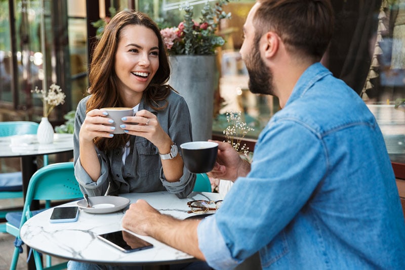mujer sonriente sentada con un hombre en un café