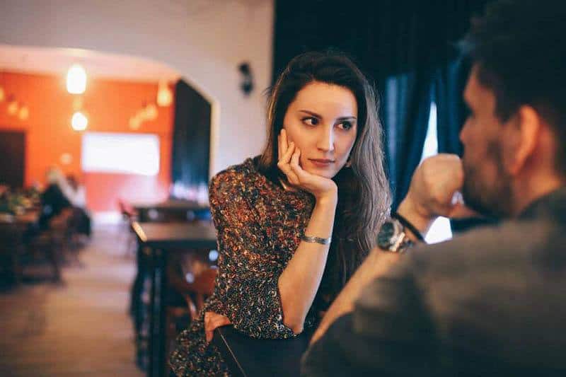 woman leaning on her hand and looking at man in cafe