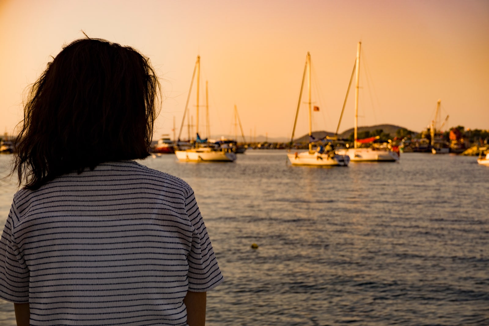 mujer sentada sola en la costa del puerto al atardecer