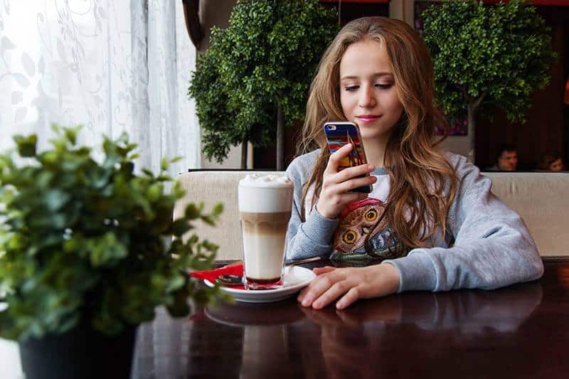 mulher a enviar mensagens de texto para o telemóvel num café