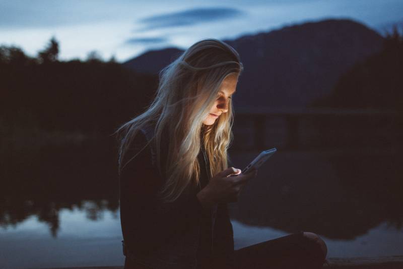 Donna che digita un sms in una serata in riva al lago