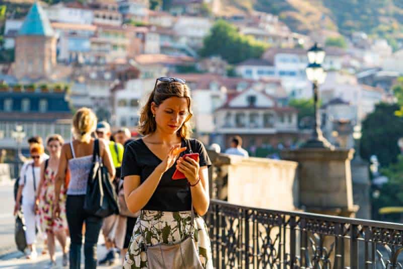 mulher a caminhar e a enviar mensagens de texto para o telemóvel