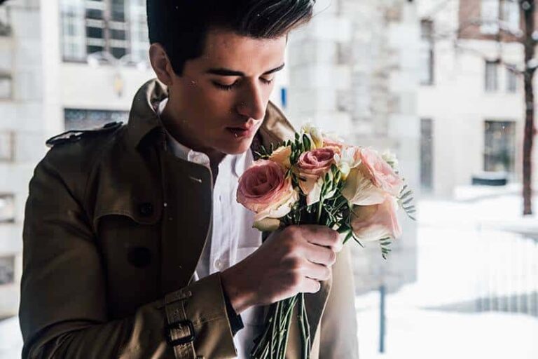 man holds roses near face