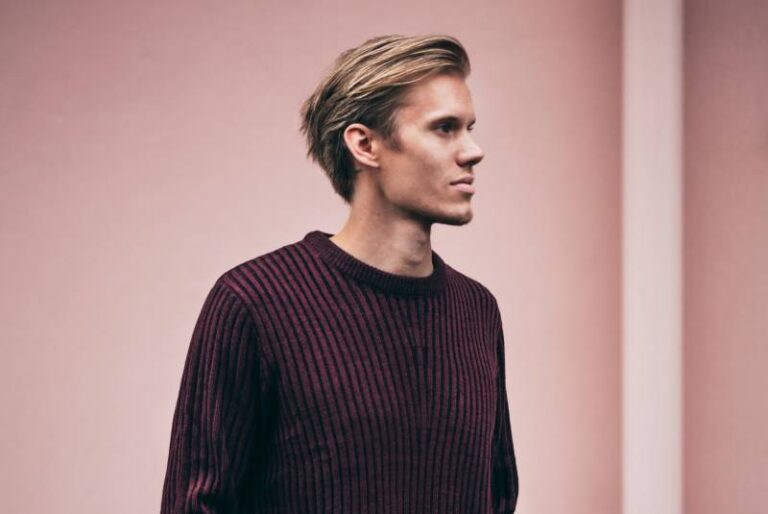 man in brown sweater standing beside wall
