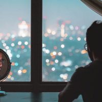 man sitting beside mirror and typing on phone