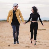 smiling couple walking on sands and holding hands