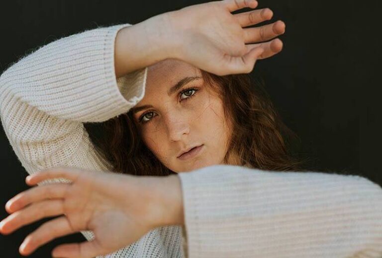 woman wearing white sweatshirt raising her hands