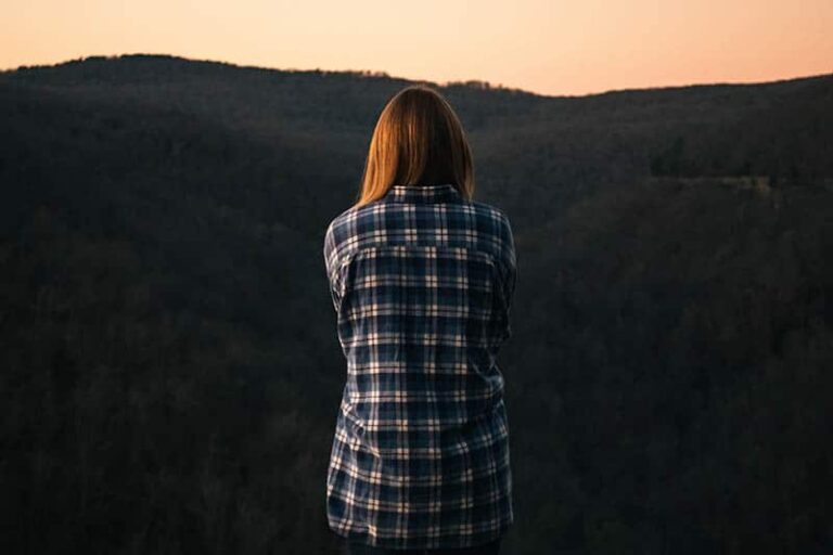 back view of woman standing in front of hills