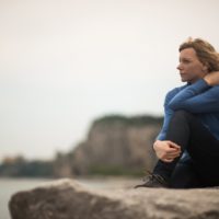 thoughtful woman sitting on a cliff