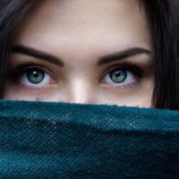 close up photo of woman with blue eyes covered her mouth