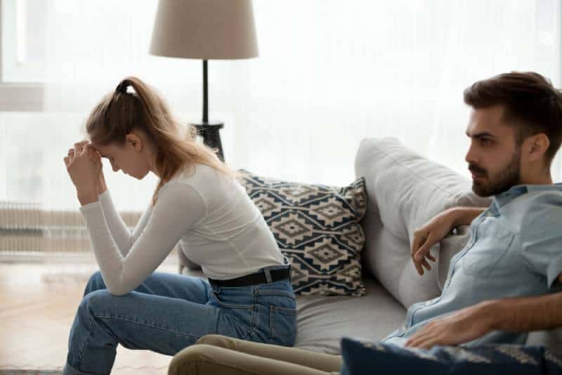 Tired unhappy couple sit separately on the couch and do not ignore excuse after fighting at home