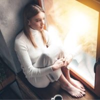 sad young woman sitting by the window