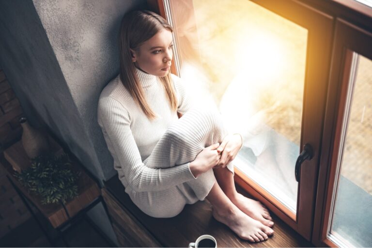 joven triste sentada junto a la ventana