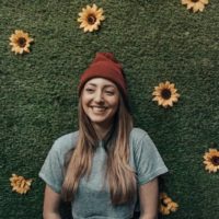 smiling woman leaning on flower wall