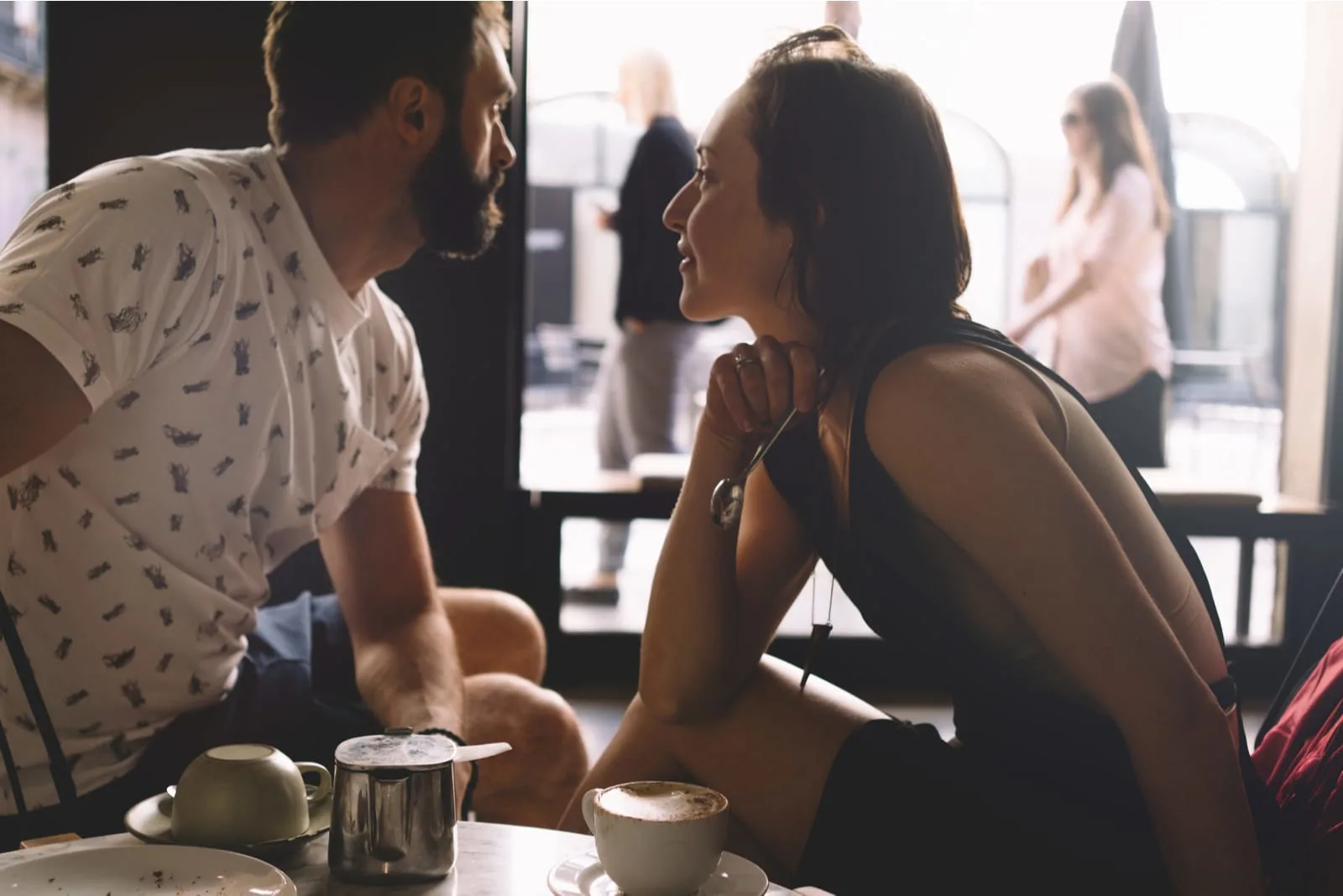 a man and a woman are sitting and drinking coffee in a cafe