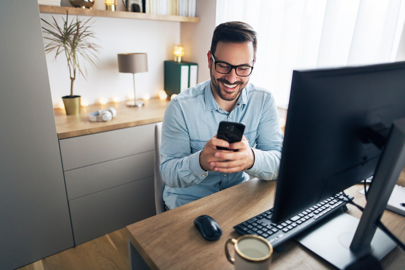 um homem senta-se numa mesa e tecla ao telefone