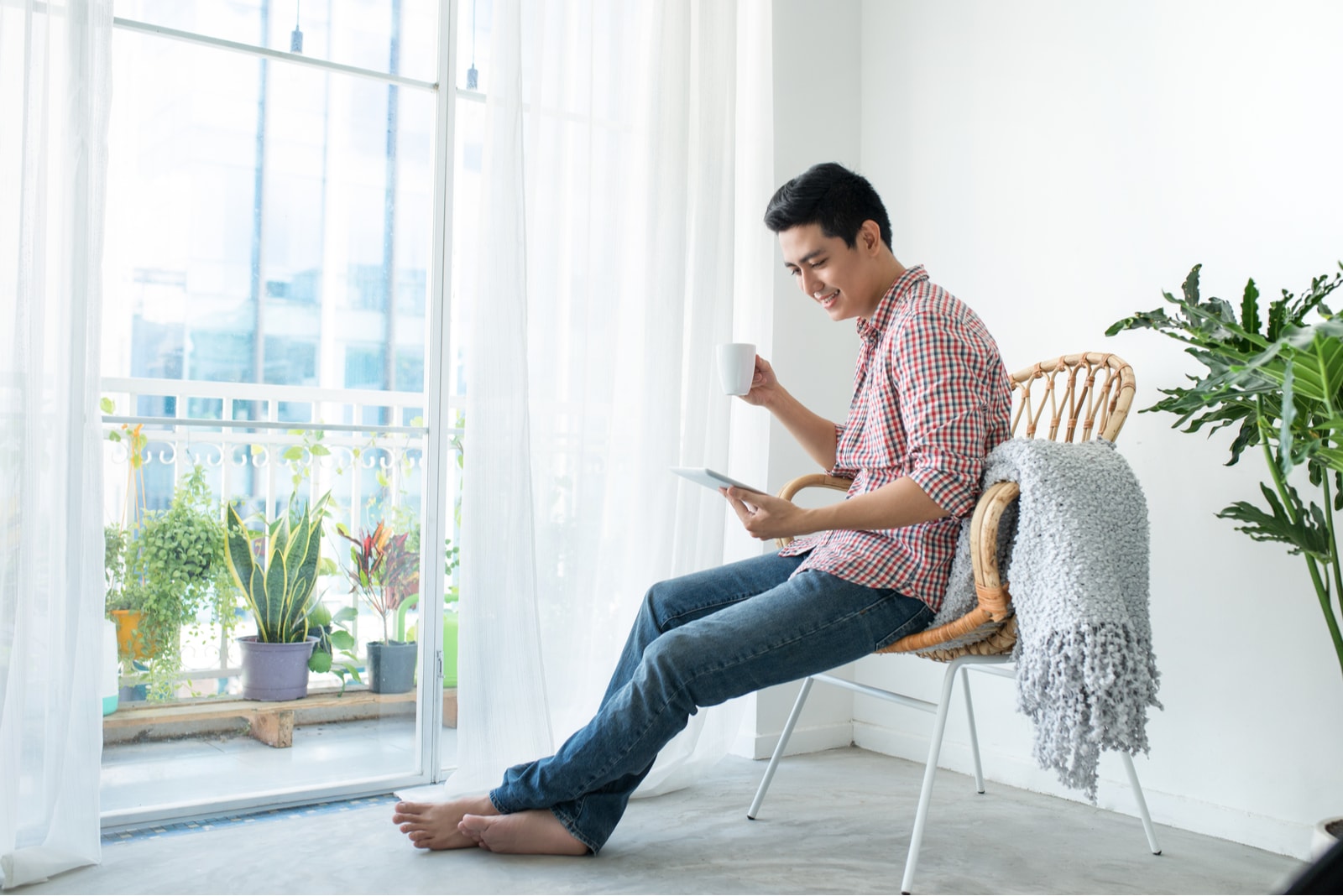 a man sitting on a chair drinking coffee and looking at the phone