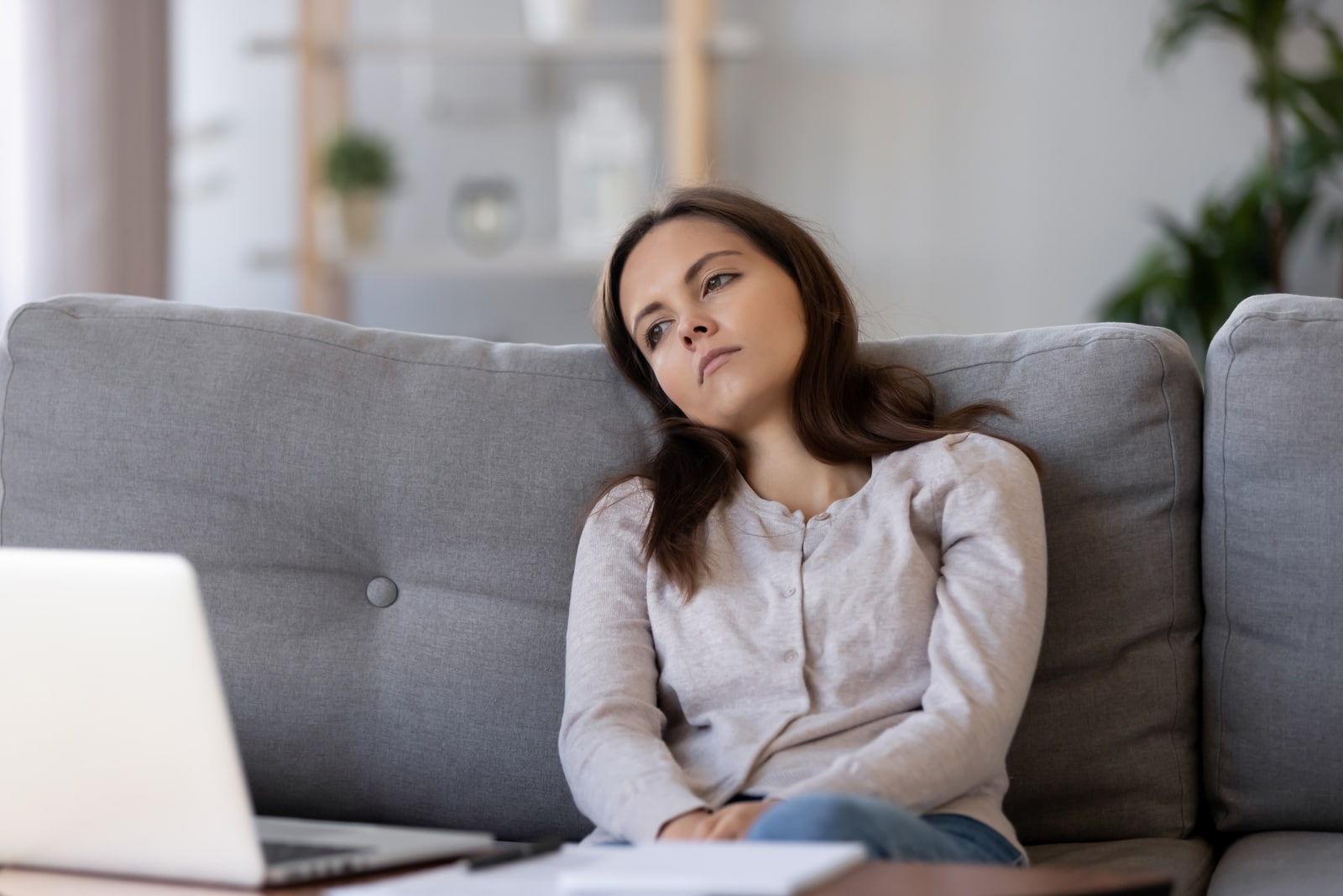 apathetic young woman looking away sitting on couch