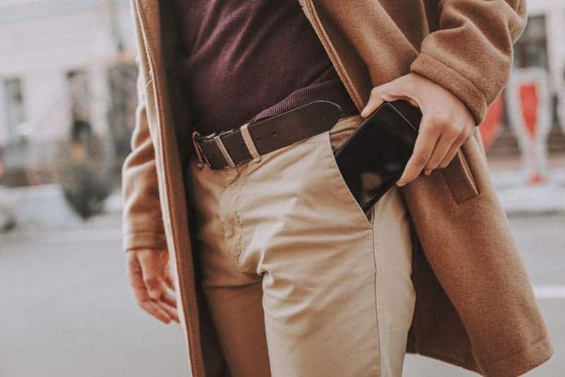 close up photo of man putting his phone in pocket
