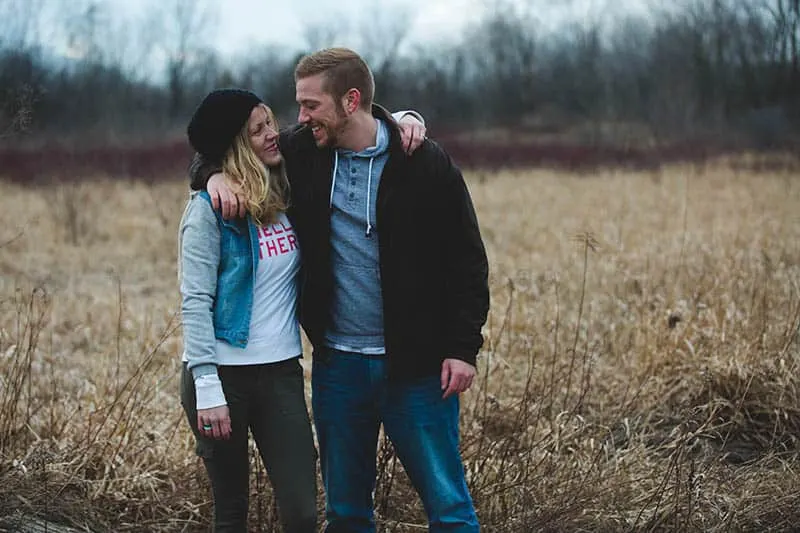 couple hugging and looking each other outside on field