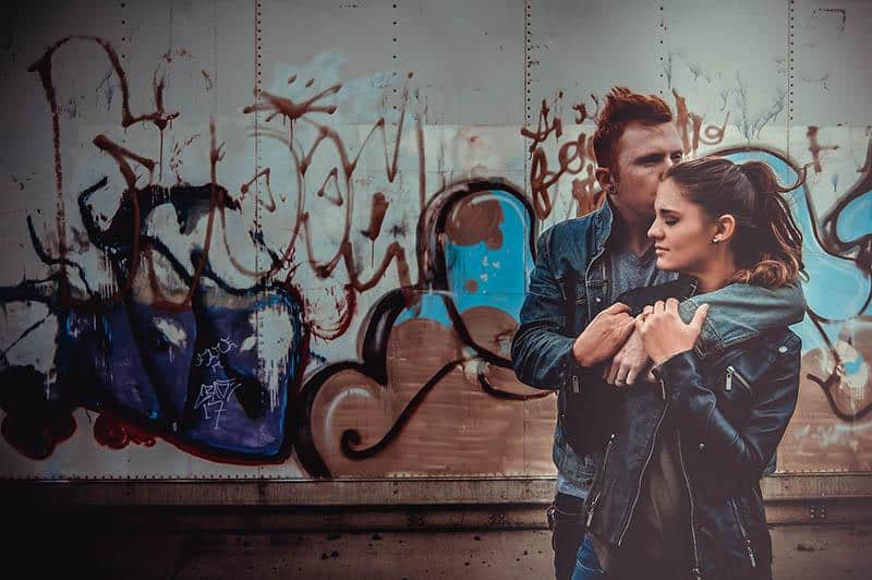 couple hugging near graffiti wall