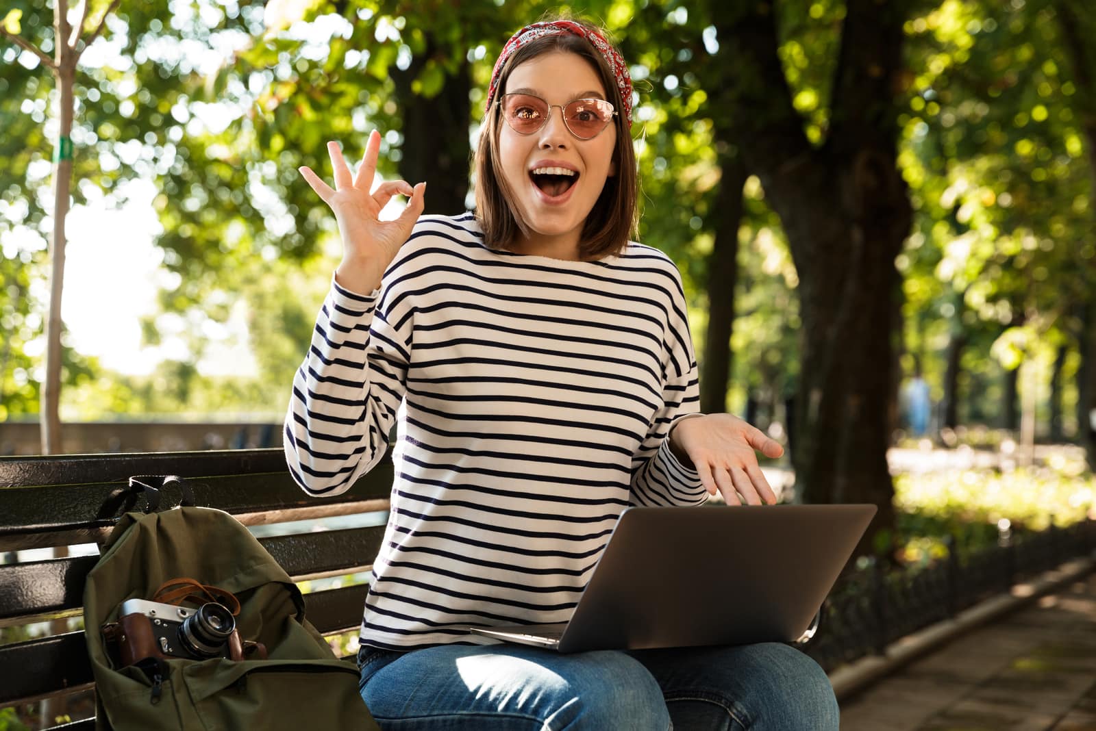 excited woman sitting on the bench with laptop