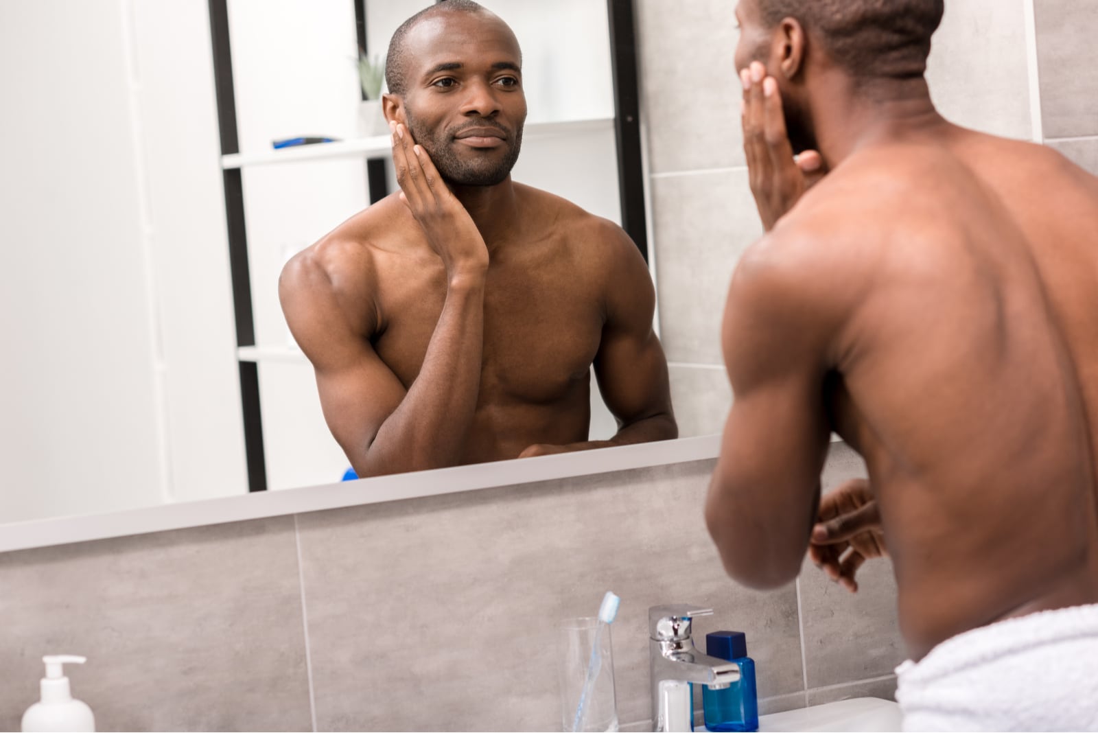 homem jovem e bonito a aplicar loção facial depois de se barbear