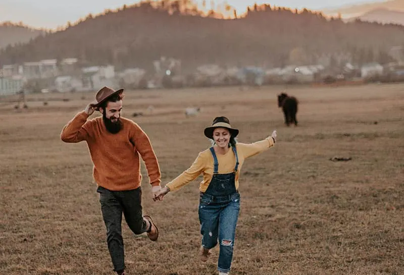 happy couple running on field in village