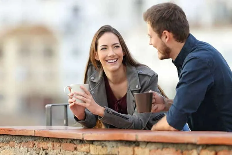 happy couple talking outside and drinking coffee