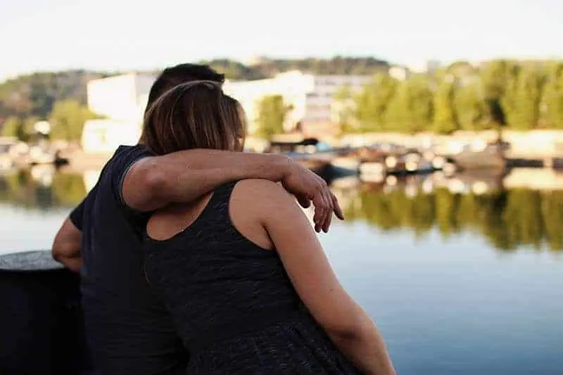 man hugging woman beside water
