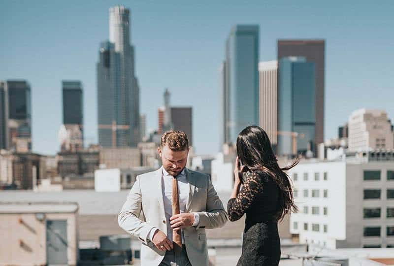 hombre con traje y mujer con vestido negro en una azotea