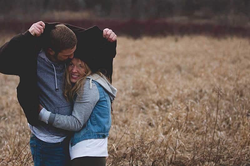 man protect woman from rain with his jacket