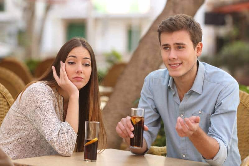 man talking to bored woman at cafe