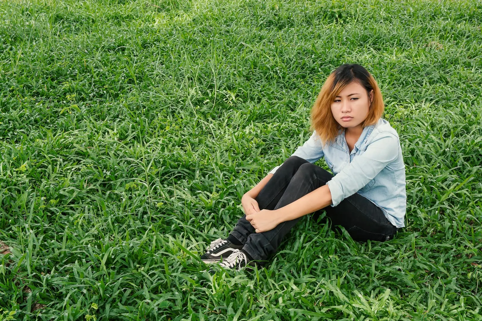 pensive woman sitting on the grass