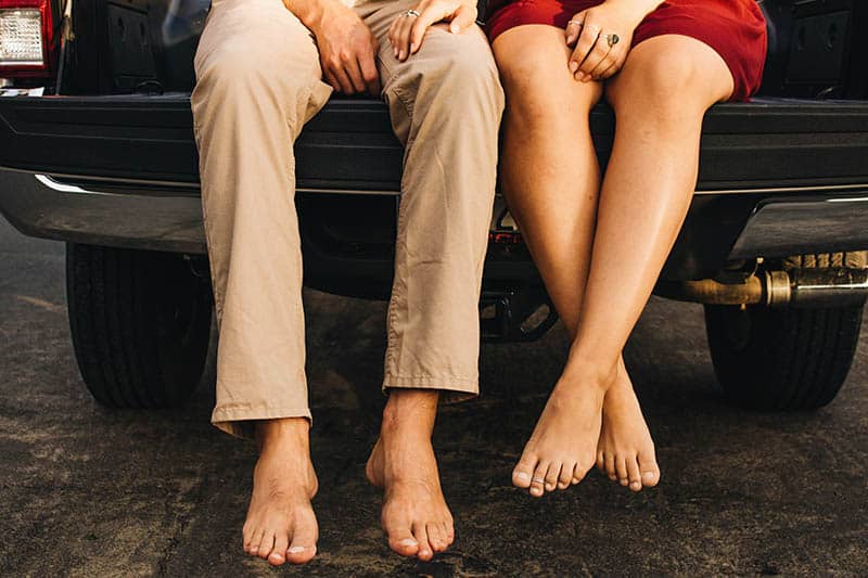 person's bare feet while sitting on car trunk
