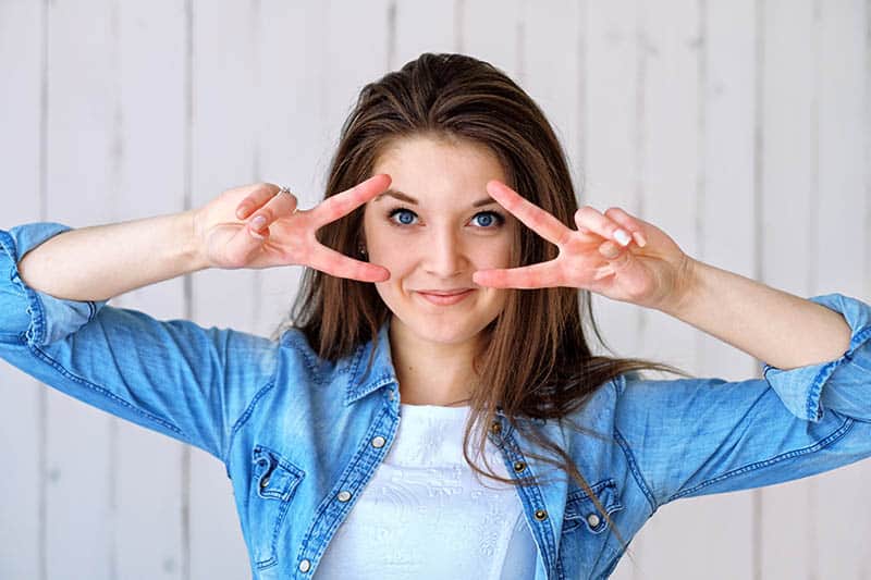 smiling woman gesturing peace signs with her hands