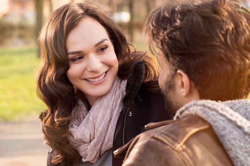 mulher sorridente a olhar para o seu homem lá fora