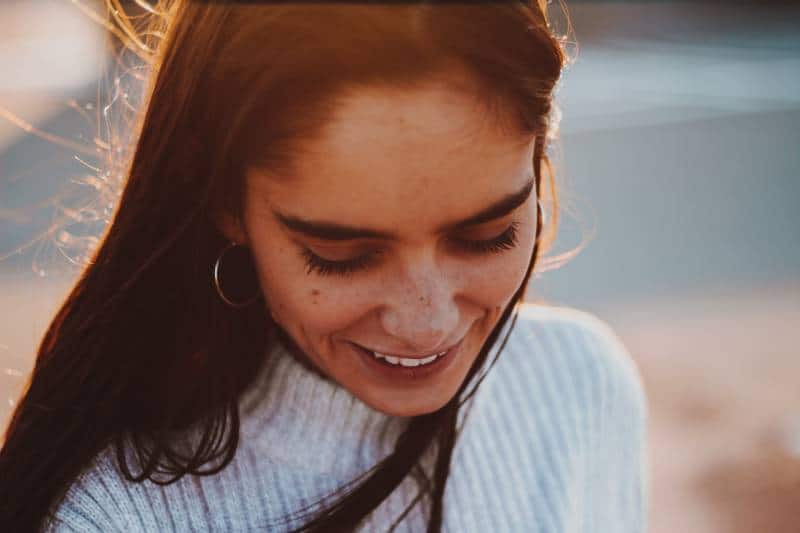 mujer sonriente con jersey de cuello alto al aire libre