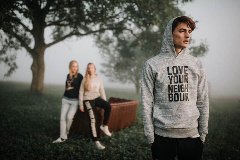 thoughtful man standing in front of two female friends outside