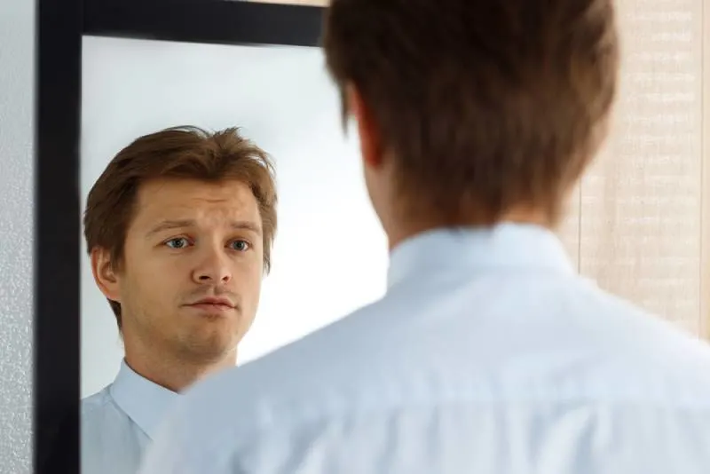 unhappy man looking at the mirror