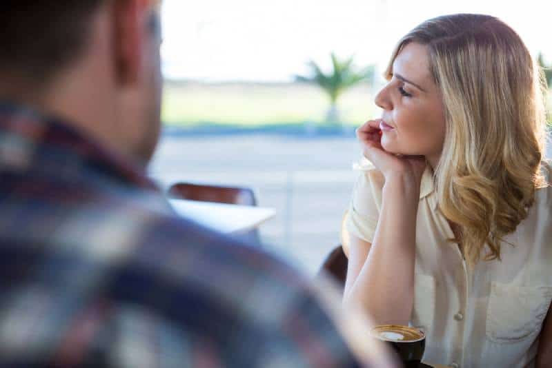 donna turbata che distoglie lo sguardo mentre è seduta con un uomo