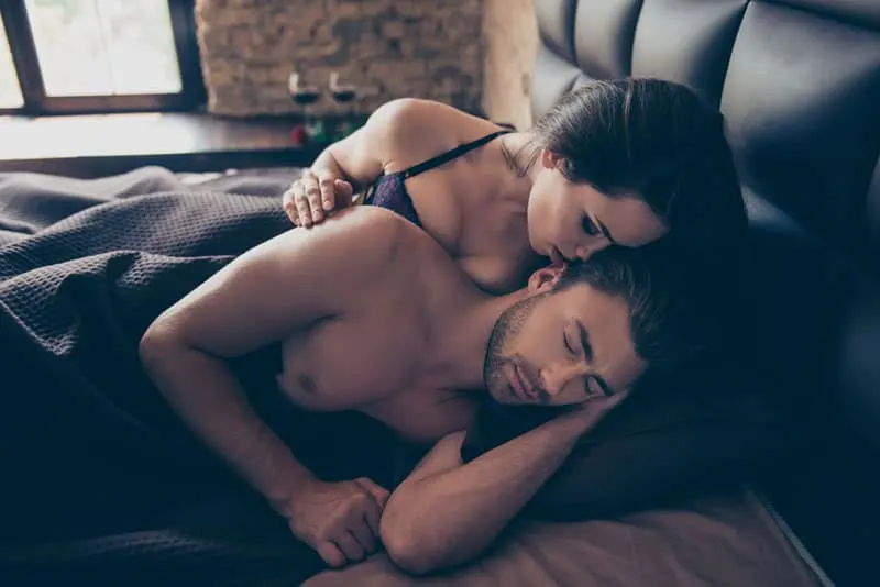 woman biting man ear in bed