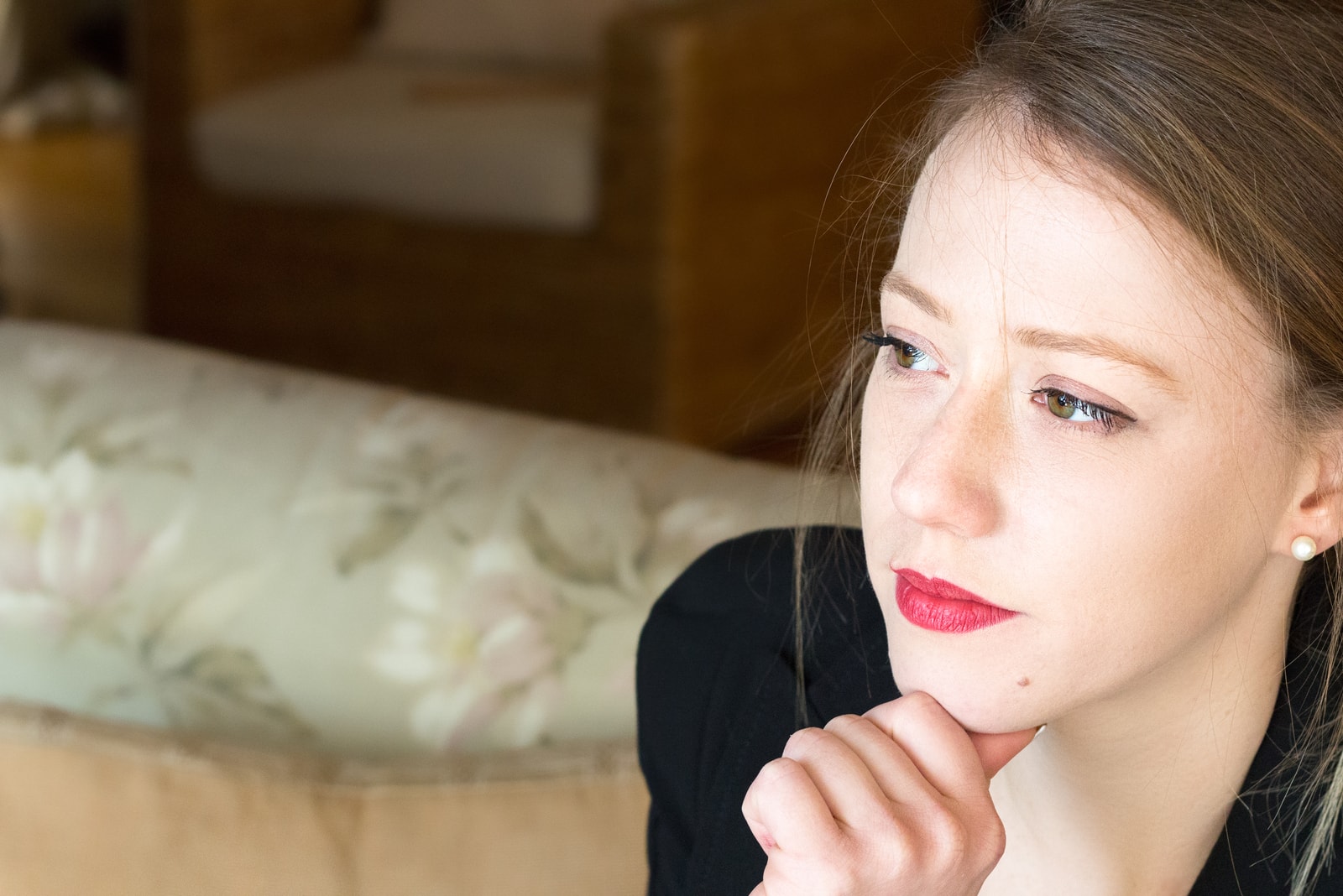  woman sitting at home with her thumb on her chin