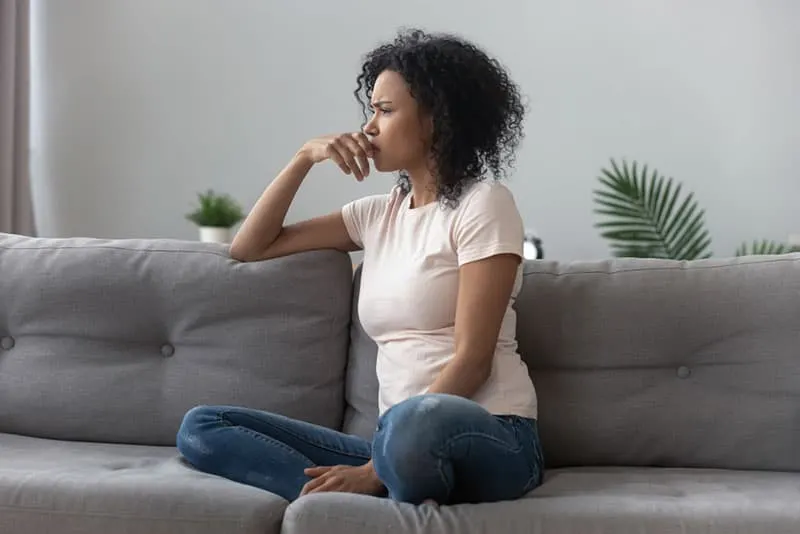 worried woman with curly hair sitting on the couch