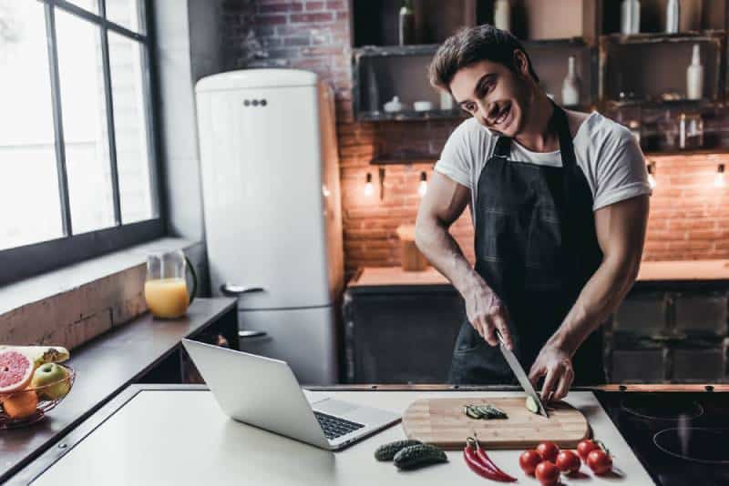 giovane uomo che cucina a casa e parla al telefono