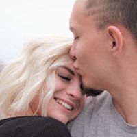 man kisses smiling blonde woman in forehead