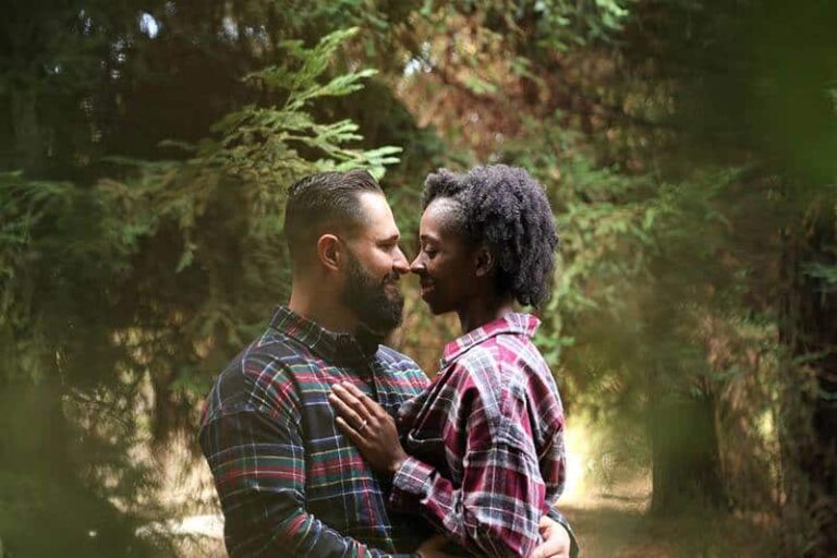 smiling couple face to face while surrounded by the nature