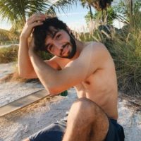 homem em topless com camisa azul na praia